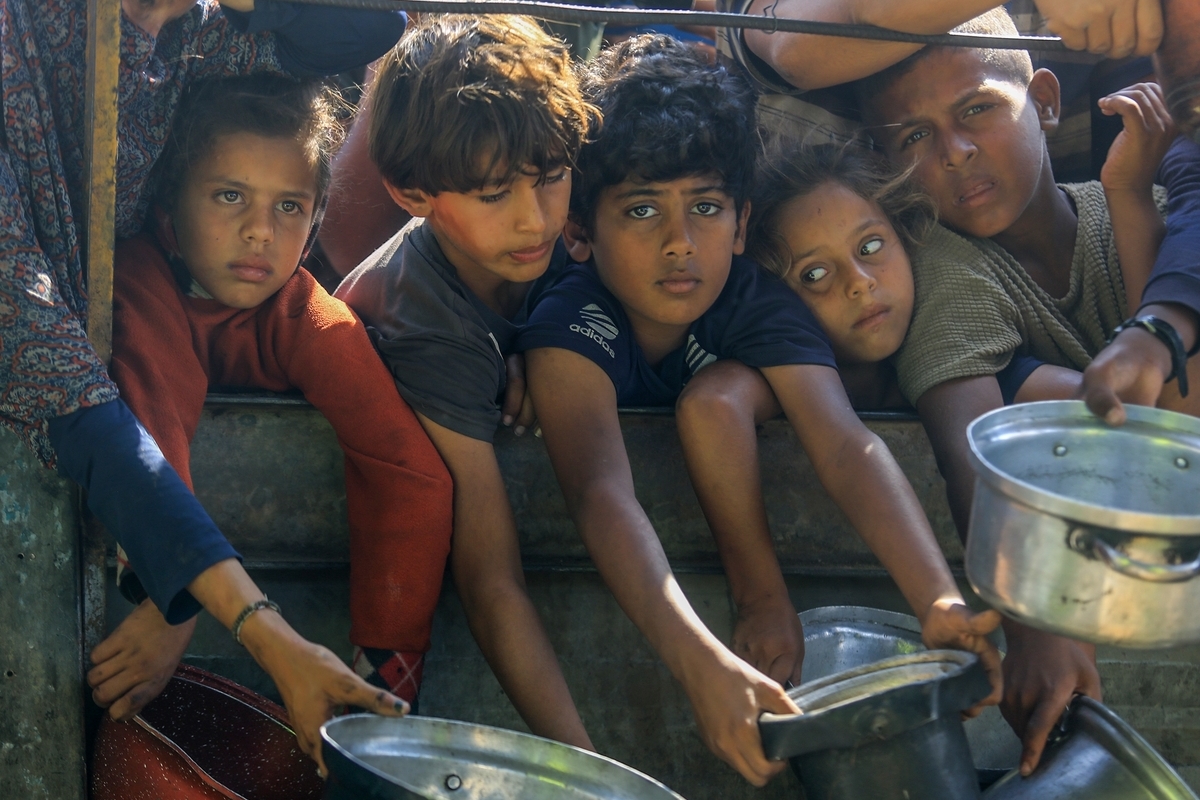 Palestinians including children, wait in long queues to receive hot meals distributed by charity organizations at al-Mawasi area in Khan Yunis, Gaza on November 5, 2025. [Abed Rahim Khatib - Anadolu Agency]