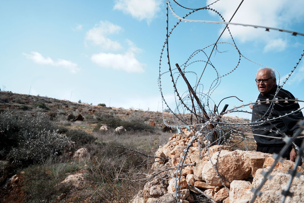 A Palestinian man looks on as Israeli construction vehicles destroy agricultural lands and uproot centuries-old olive trees in the village of Karyut, south of the city of Nablus, West Bank on December 08, 2025. [Issam Rimawi - Anadolu Agency]