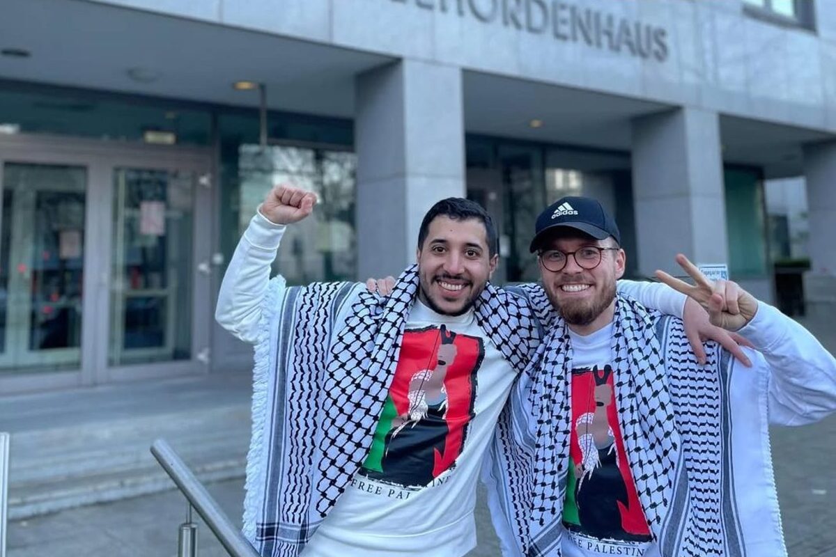 This image shows Ahmad Othman (L) celebrating a legal victory on March 26, 2026, in front of the Landesbehördenhaus in Dortmund, Germany