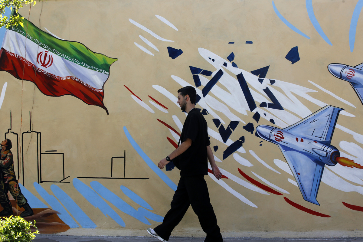 Residents walk past colorful wall paintings as daily life continues under the shadow of destruction following the U.S. and Israeli attacks on Tehran, Iran, on April 5, 2026. [Fatemeh Bahrami - Anadolu Agency]
