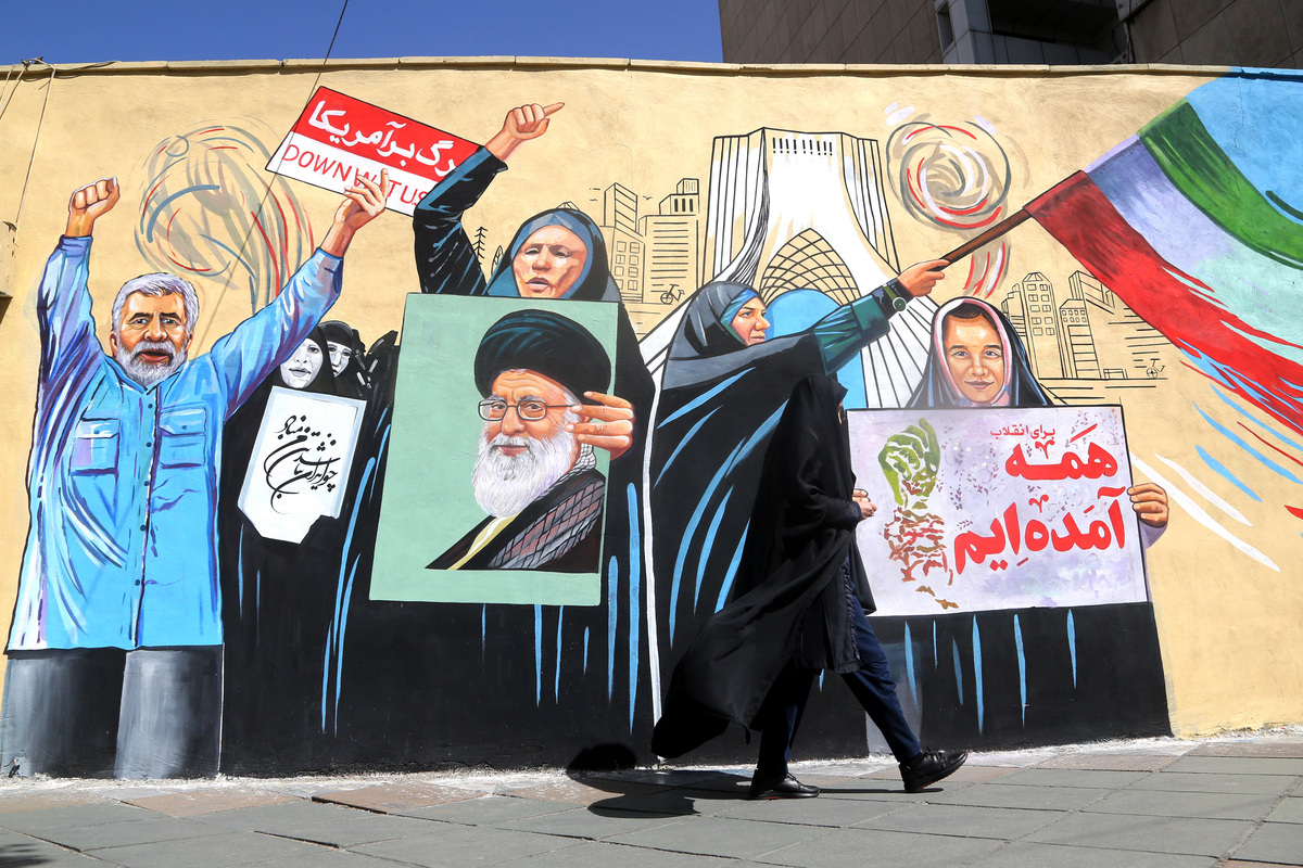 Residents walk past colorful wall paintings as daily life continues under the shadow of destruction following the U.S. and Israeli attacks on Tehran, Iran, on April 5, 2026. [Fatemeh Bahrami - Anadolu Agency]