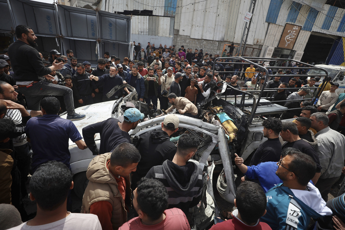 Palestinians inspect the damaged car after an Israeli airstrike targeting a police vehicle killed four Palestinians and injured many others in Gaza City, Gaza, Palestine on April 14, 2026. [Khames Alrefi - Anadolu Agency]