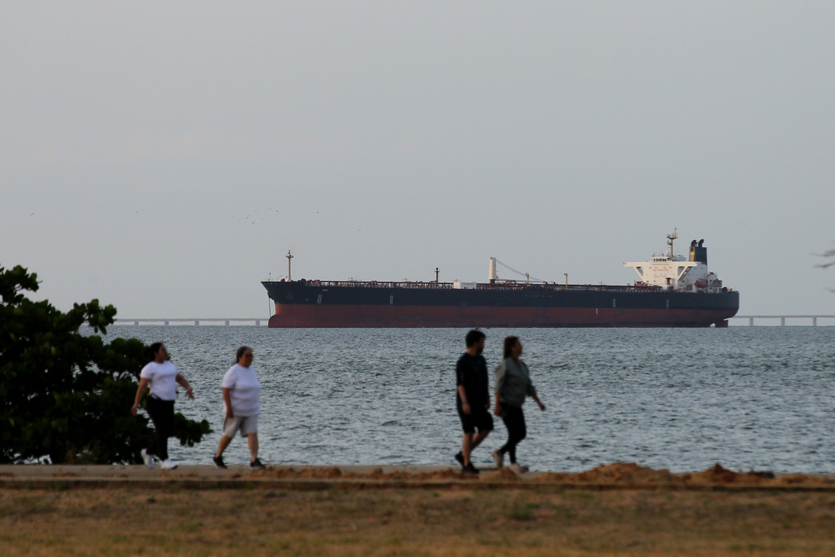 People pass by as an oil tanker is seen on Lake Maracaibo, loaded with petroleum, waiting to depart for refineries in the United States, in Maracaibo, Venezuela, on May 11, 2026. [Jose Isaac Bula - Anadolu Agency ]