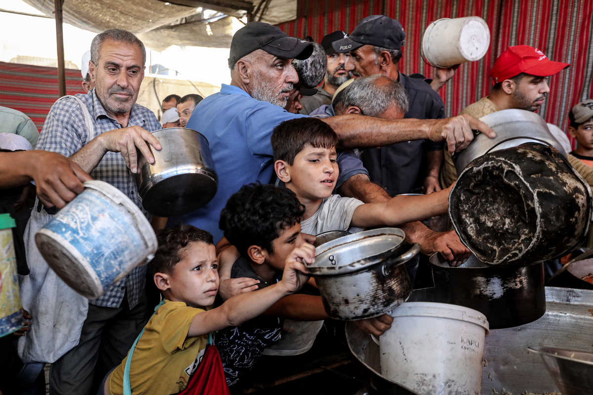Displaced Palestinians, including many children, wait in long queues to receive hot meals distributed by a charitable organization in Gaza City, Gaza, Palestine on June 07, 2026. [Moiz Salhi - Anadolu Agency]